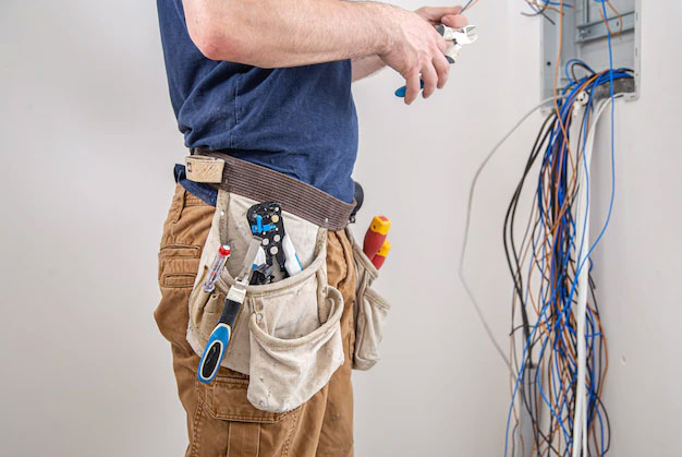 electrician-builder-work-examines-cable-connection-electrical-line-fuselage-industrial-switchboard-professional-overalls-with-electrician-s-tool